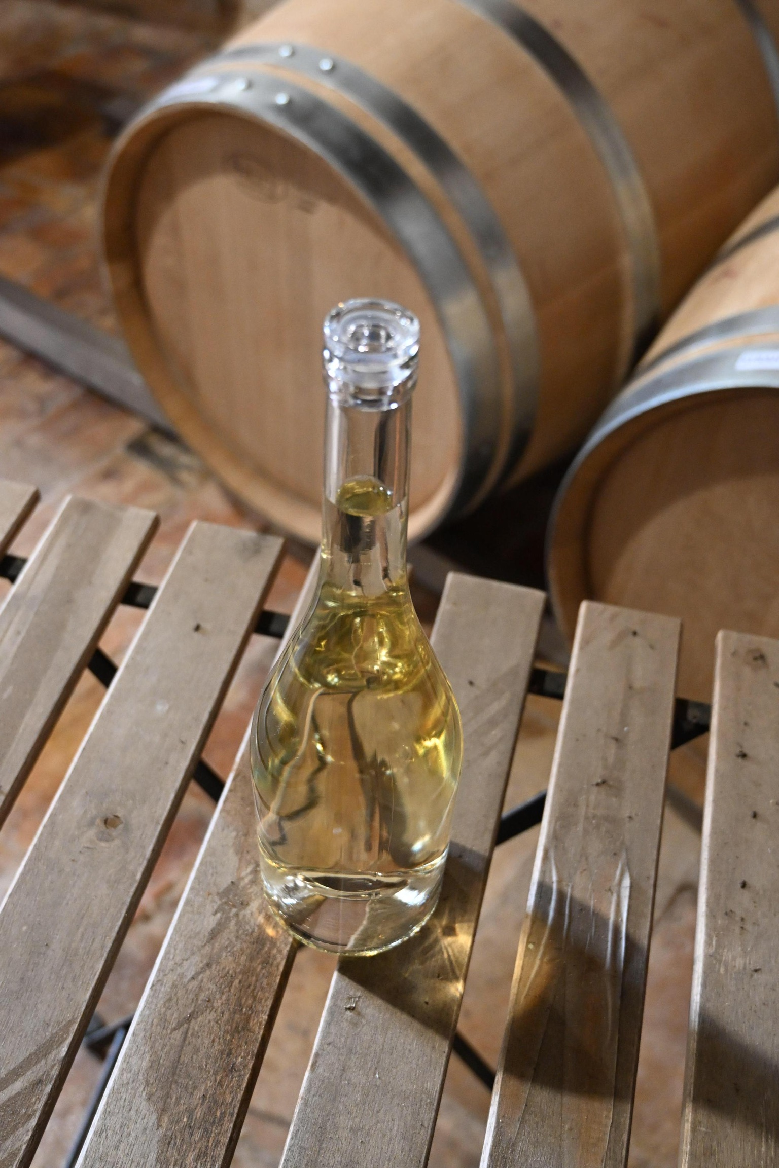 Botella de Nautilus sobre una mesa de madera junto a las barricas de la bodega